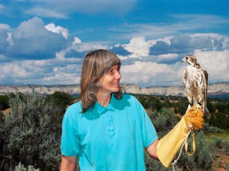 Vintage photo of Sharon St. Joan holding a bird of prey with cliffs and a beautiful sky in the background