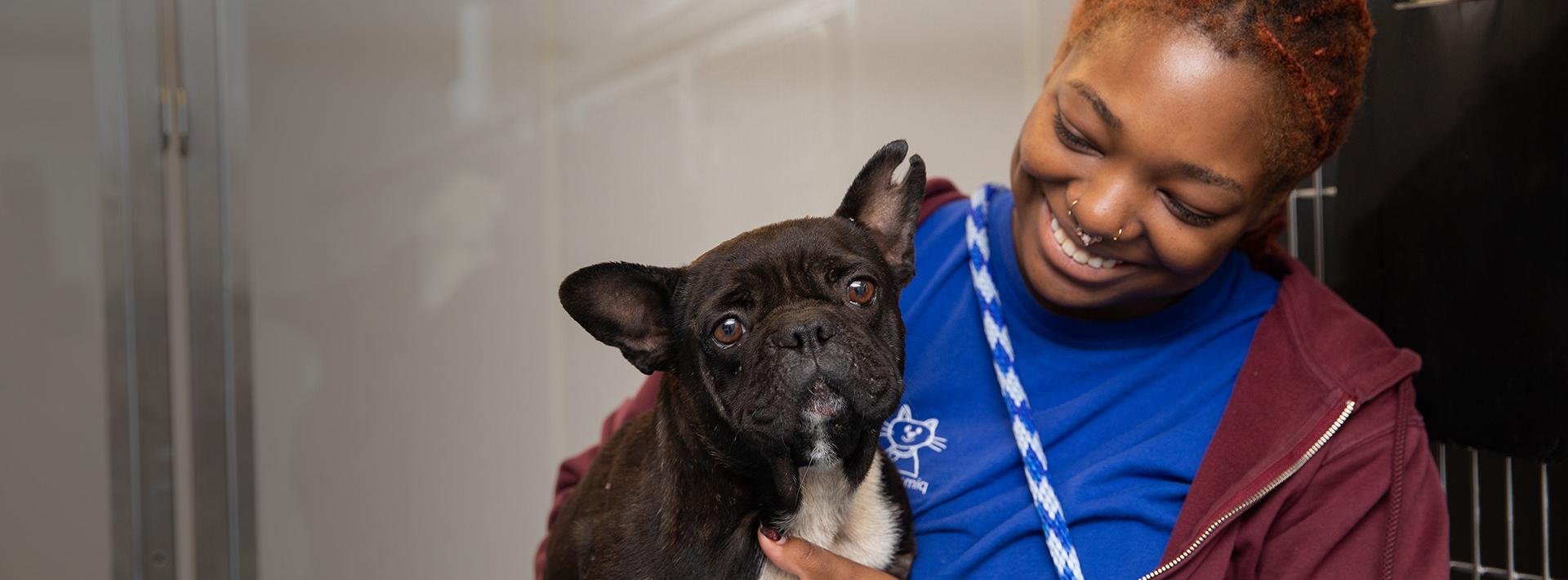 Woman smiling at dog in her arms.